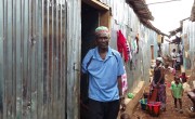 Man stands outside his new home in Kroo Bay.