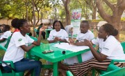Three African women and one man writing list at green plastic table
