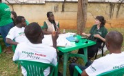 Concern staff members speaking to three men in white t-shirts reading 'climate justice now'
