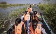 Five men in Concern life-jackets travelling through flood water on canoe