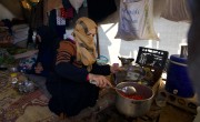 Reem* (30) prepares food for her husband Jaafar* (32) and her children inside their tent in the Ahl al-Khair camp, Syria.