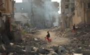 Child on tricycle cycles through destroyed buildings in Gaza
