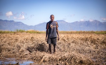 Recently married Patrick Ghembo of Monyo Village standing in his field, destroyed by the floods. Patrick is a farmer of maize and rice. He must rely solely on fishing until he can plant again. His wife and him will stay at the displacement camp until the floods have fully subsided. Photo: Gavin Douglas/ Concern Worldwide.