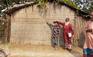 Community members in Vati Kapasia, Kapasia Union, Sundarganj, Bangladesh show the level of the flood water from the 2019 monsoon on their home. Photo: Finola Mohan / Concern Worldwide.