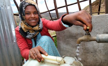 Young girl collecting water from a source built in Ethiopia