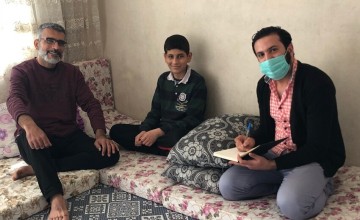 Schoolboy sitting in between two men and smiling