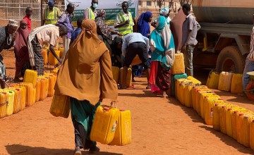 Woman carrying water cans and walking towards truck