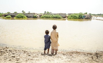 Children look across the floodwaters in Sindh province, Pakistan, where millions of people need urgent help. DEC charity Islamic Relief is providing emergency food and temporary shelter as families do all they can to keep safe and survive. Photo: Islamic Relief