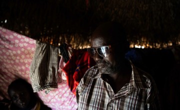 Man wearing dark glasses, in front of hanging laundry