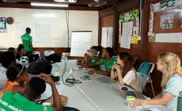 Group of people sitting at table in office, looking at whiteboard