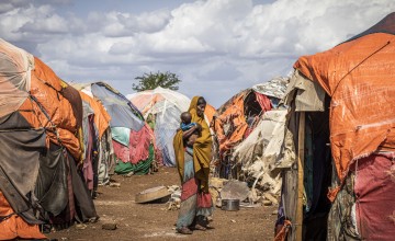 Woman holding baby in the middle of makeshift camp