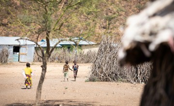 Children walking near wooden hut