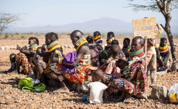 Group of African women in colourful beaded necklaces sitting on the ground