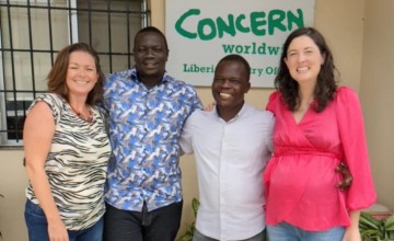 Two women and two men smiling in group picture outside Concern office
