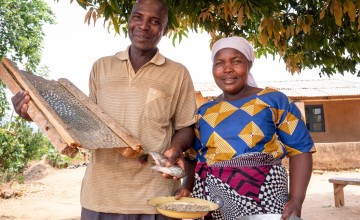 Man holding fish, next to wife holding plate of fish food