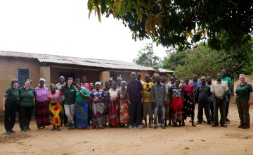 Large group of men and women standing in front of house