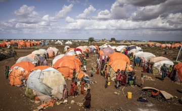 Orange and white makeshift tents surrounded by children in Somalian IDP settlement