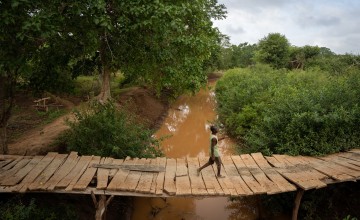 A man uses a small bridge to cross a river in Mikemani village, Tana River County. Photo: Zurich Flood Resilience Alliance/Concern Worldwide