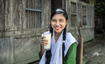 Fourteen year old Nazma Akter is drinking milk before leaving for school. She often participates in group discussions in the yard meeting conducted by Concern Worldwide and its partner organizations to gain knowledge about healthy food, health and hygiene, gender, and social safety issues. The Collective Responsibility, Action, and Accountability for Improved Nutrition (CRAAIN) project have educated them to act right about nutrition and safeguarding health.