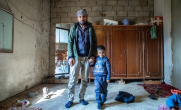 Khaled and his son in their house