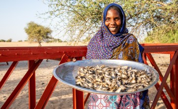 Aicha shows off fish the fishing association caught and dried