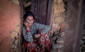 Tulasa Aryal, 58, sits on the porch of her destroyed home in Bakrang, a village near the epicenter of the 2015 earthquake. (Photo: Kieran McConville/Concern Worldwide)