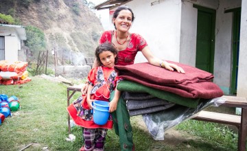 Chameli Darji, 35, with her youngest daughter, Apita, six, with the items they received at a Concern Worldwide and Rural Reconstruction Nepal (RRN) distribution in Talamarang VDC in Sindhupalchok district, Nepal, one of the hardest hit areas by the 7.8-magnitude earthquake that hit the country on April 25, 2015. (Photo: Crystal Wells/Concern Worldwide)