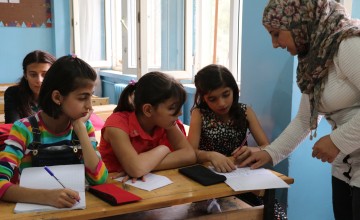 A teacher helps young students with their school work.