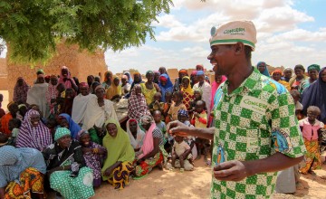 Assoumane Tssiako, a member of the Ecole des Maris, stands on front of his community. Photo: Jennifer Nolan/Concern Worldwide.