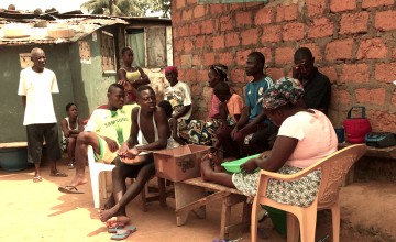 A quarantined family sit in the shade of their home in Liberia. Photo taken by Concern Worldwide.
