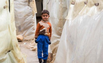 A young Syrian refugee stands between the tents at an informal settlement in the north of Lebanon. Photo: Dalia Khamissy / Concern Worldwide.
