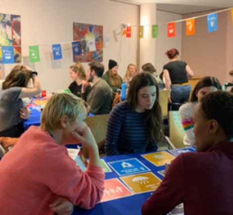 Room filled with tables and bunting with people discussing SDGs