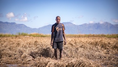 Recently married Patrick Ghembo of Monyo Village standing in his field, destroyed by the floods. Patrick is a farmer of maize and rice. He must rely solely on fishing until he can plant again. His wife and him will stay at the displacement camp until the floods have fully subsided. Photo: Gavin Douglas/ Concern Worldwide.