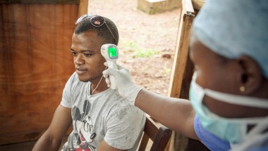 A visitor (Wilson Amadu) to Allen Town PHU has his temperature taken before entering the PHU. All patients and visitors are screened for symptoms of Ebola before entering the PHU. Photographer: Michael Duff.