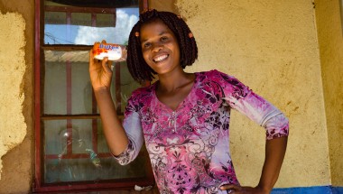 Smiling young woman Alice Eneya holds up soap she received from Concern.