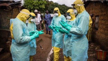 A burial team pray before they collect a corpse from inside a house in the east of Freetown Sierra Leone in 2015 Ebola outbreak. Photograph: Michael Duff