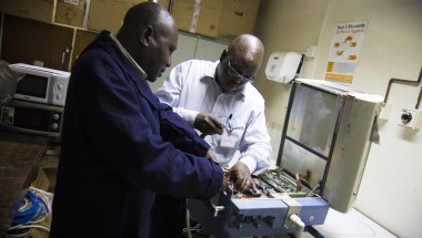 Shadrack Wamwayi and Steve Belle, biomedical engineers working on equipment at the Kenyatta National Hospital, Nairobi, Kenya, 2014. Photo: by Crystal Wells / Concern Worldwide.