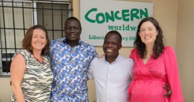 Two women and two men smiling in group picture outside Concern office