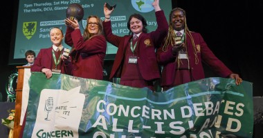 Four team members from Laurel Hill Secondary school stand on a stage with a banner in front of them, after receiving their awards for winning the Concern 2025 Debate final
