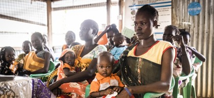 Mother holding her baby in busy health clinic waiting room