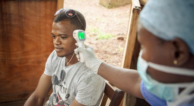 A visitor (Wilson Amadu) to Allen Town PHU has his temperature taken before entering the PHU. All patients and visitors are screened for symptoms of Ebola before entering the PHU. Photographer: Michael Duff.
