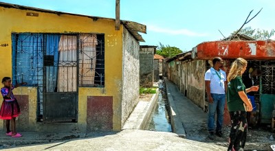 Concern staff member speaking to people against brightly coloured houses in shanty town