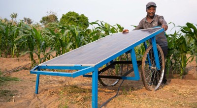 Man in cap and t-shirt holding onto solar water pump