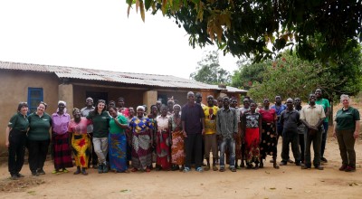 Large group of men and women standing in front of house