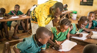 Teacher John Kabia assists students at Patiful Mayeppuh SDA Primary School in Sierra Leone Photo: Michael Duff/Concern Worldwide
