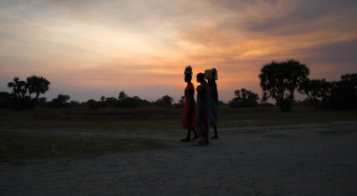 Women crossing in Leer County, Unity State, South Sudan at sunset. Deep in the swamps, the island has become a haven for thousands of people fleeing conflict. Photo: Kieran McConville/Concern Worldwide