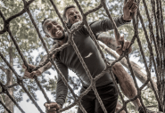Two men covered in mud climbing rope ladder